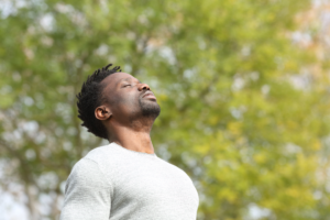 African-American man standing outside holding his breath with his eyes closed